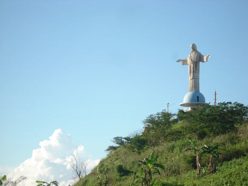 Estátua do Cristo Redentor de Itaperuna no topo do morro, acima da vegetação