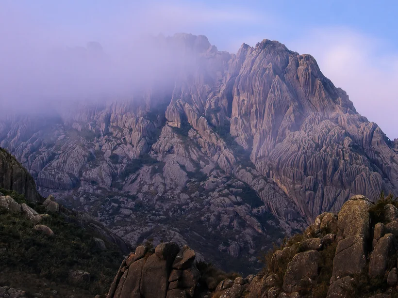 Pico das Agulhas Negras na luz do amanhecer, com neblina entre as rochas