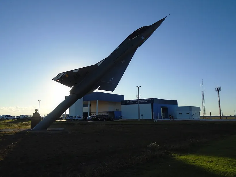 Terminal do aeroporto de Sorriso ao fim da tarde, com o monumento de um caça em primeiro plano